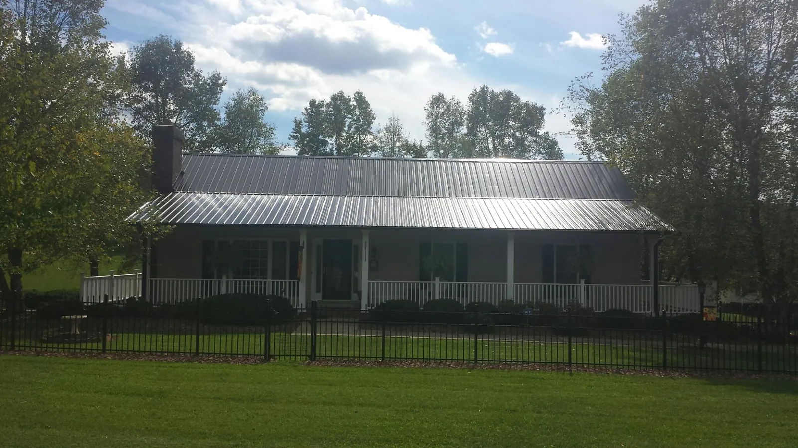 Gray metal roof on a brick ranch with a full width front porch — Gutter Guard Installation work by our crew in Somers