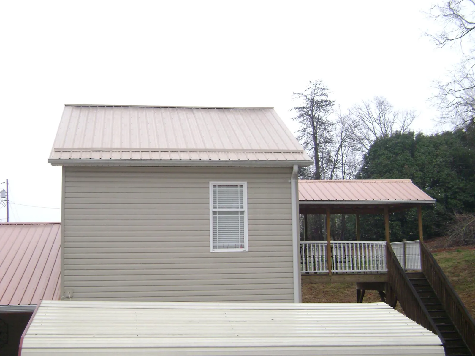 Tan metal roofs on a two story addition and attached porch, from a Roof Replacement job in Somers