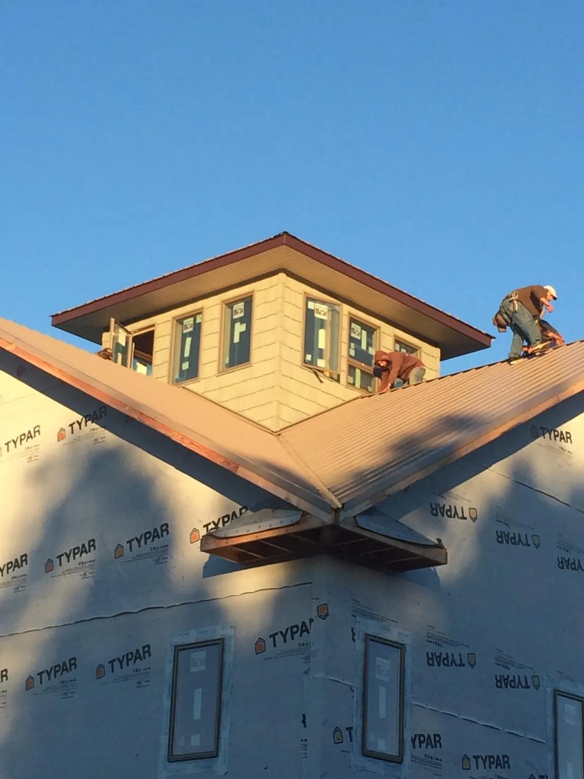 Roofers working around a rooftop cupola on a new metal roof at sunset — Roof Waterproofing in Somers by Roofing Brothers